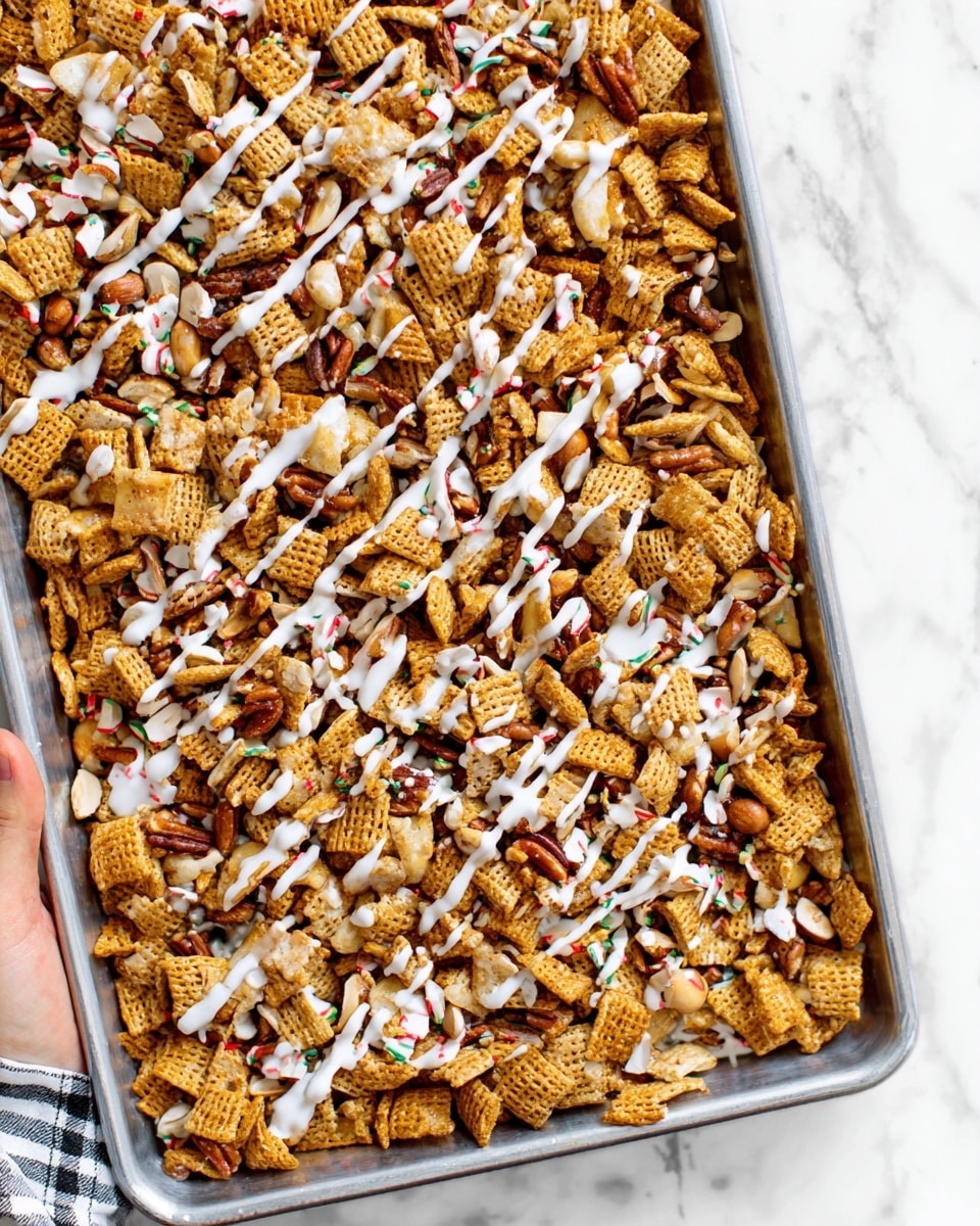 The image shows a close-up of a tray filled with a crunchy snack mix. The mix has several layers: the bottom layer is made up of small, square, light brown cereal pieces with a rough texture. Sprinkled all over are light-colored nuts and small, thin crackers that add depth to the mix. On top, a white drizzle is spread in thin, random lines across the whole mix, contrasting with the darker colors of the cereal and crackers. The whole snack appears slightly shiny, suggesting a sticky or sweet coating. The tray sits on a white marbled surface, and a woman's hand is visible in the bottom left, holding the tray corner. photo taken with an iphone --ar 4:5 --v 7