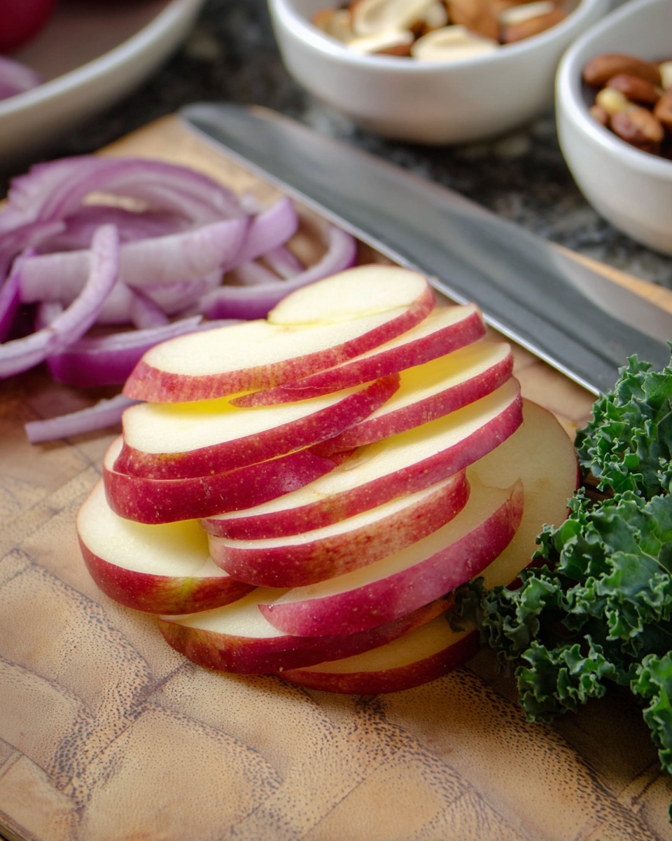 The image shows thin slices of red apple neatly stacked in the center, with bright red skin and light yellow flesh visible, creating two layers of color. To the left, there are a few slices of purple onion with a smooth, shiny texture, arranged in a curved shape. On the right side, a small bunch of dark green curly kale leaves adds texture and color contrast. A large silver knife lies behind the apple slices, and in the blurry background, two white bowls contain brown and white nuts, all placed on a wooden cutting board with a natural grain pattern. The photo taken with an iphone --ar 4:5 --v 7