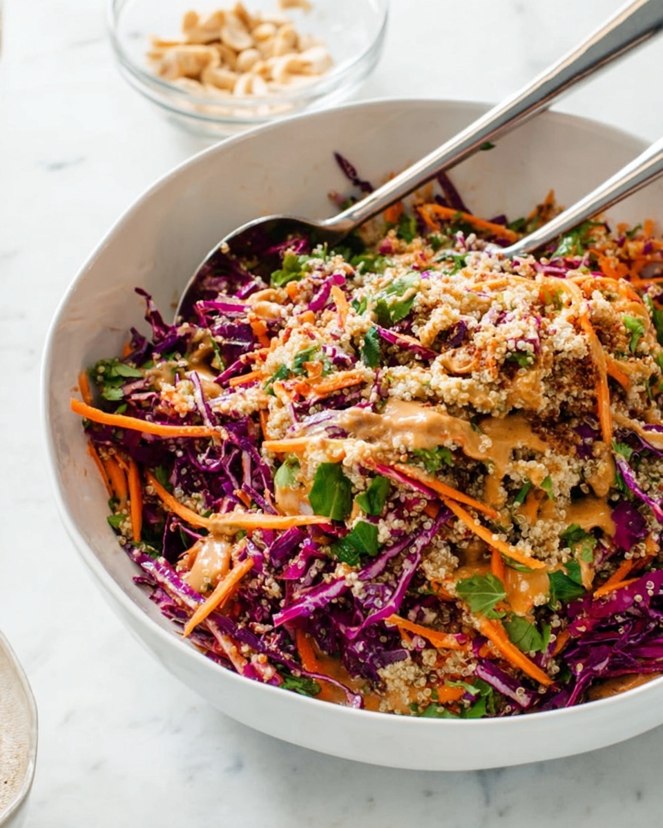 A white bowl filled with a colorful salad showing three main layers: the bottom layer has shredded bright purple cabbage, the middle layer contains thin orange carrot strips mixed with green leafy herbs, and the top layer is topped with fluffy light beige quinoa grains and drizzled with a light brown dressing. Two metal serving spoons rest in the bowl among the salad, and the bowl sits on a white marbled surface with a small glass bowl of light-colored nuts or seeds in the background. photo taken with an iphone --ar 4:5 --v 7