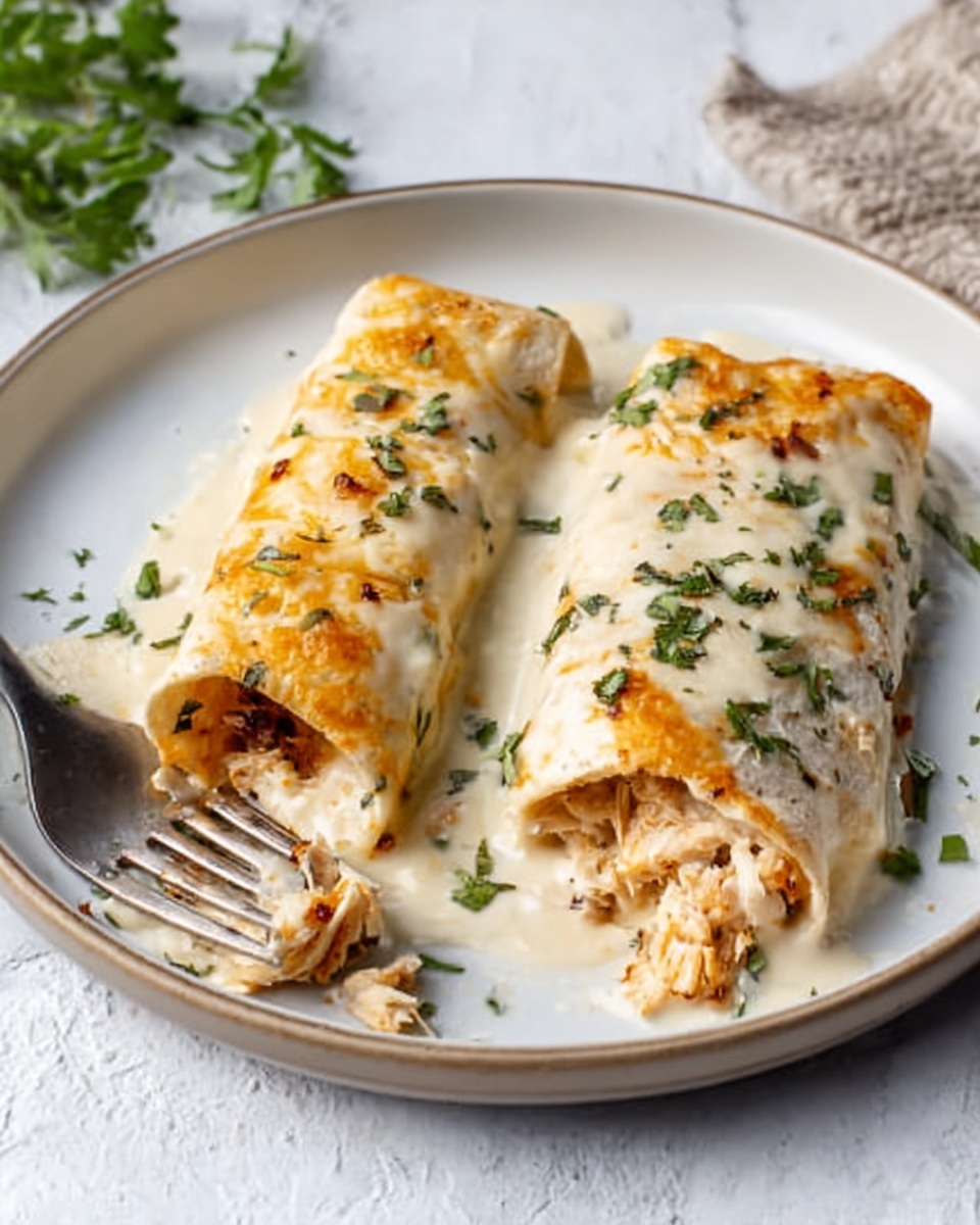 The image shows a close-up of two rolled enchiladas on a white plate, placed on a white marbled surface. The enchiladas have a soft, light golden outer layer with some browned spots and are filled with a reddish-orange mixture that hints at a savory filling with small bits of vegetables or meat inside. The top of the enchiladas is covered with melted white cheese, sprinkled with finely chopped green herbs. A silver fork rests next to the enchiladas on the plate. photo taken with an iphone --ar 4:5 --v 7