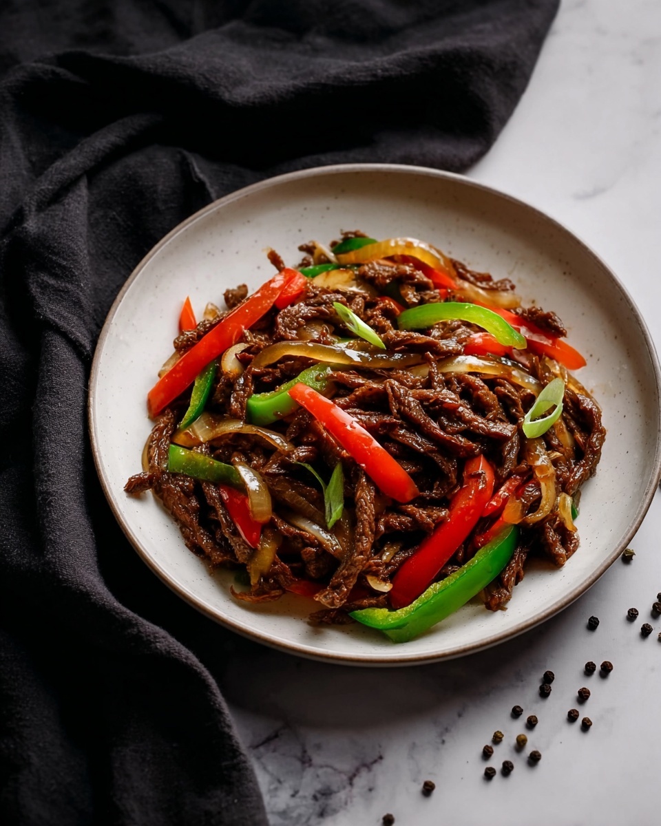 The image shows a white plate filled with a stir-fry dish. The dish has several layers: a base of thin, dark brown strips of cooked meat mixed with long, thin slices of red and green bell peppers and translucent onion strips. The vegetables are glossy and vibrant, adding a pop of color to the dark meat. The plate rests on a white marbled surface, and some scattered black peppercorns are visible around it. A dark cloth is draped casually in the background. Photo taken with an iphone --ar 4:5 --v 7