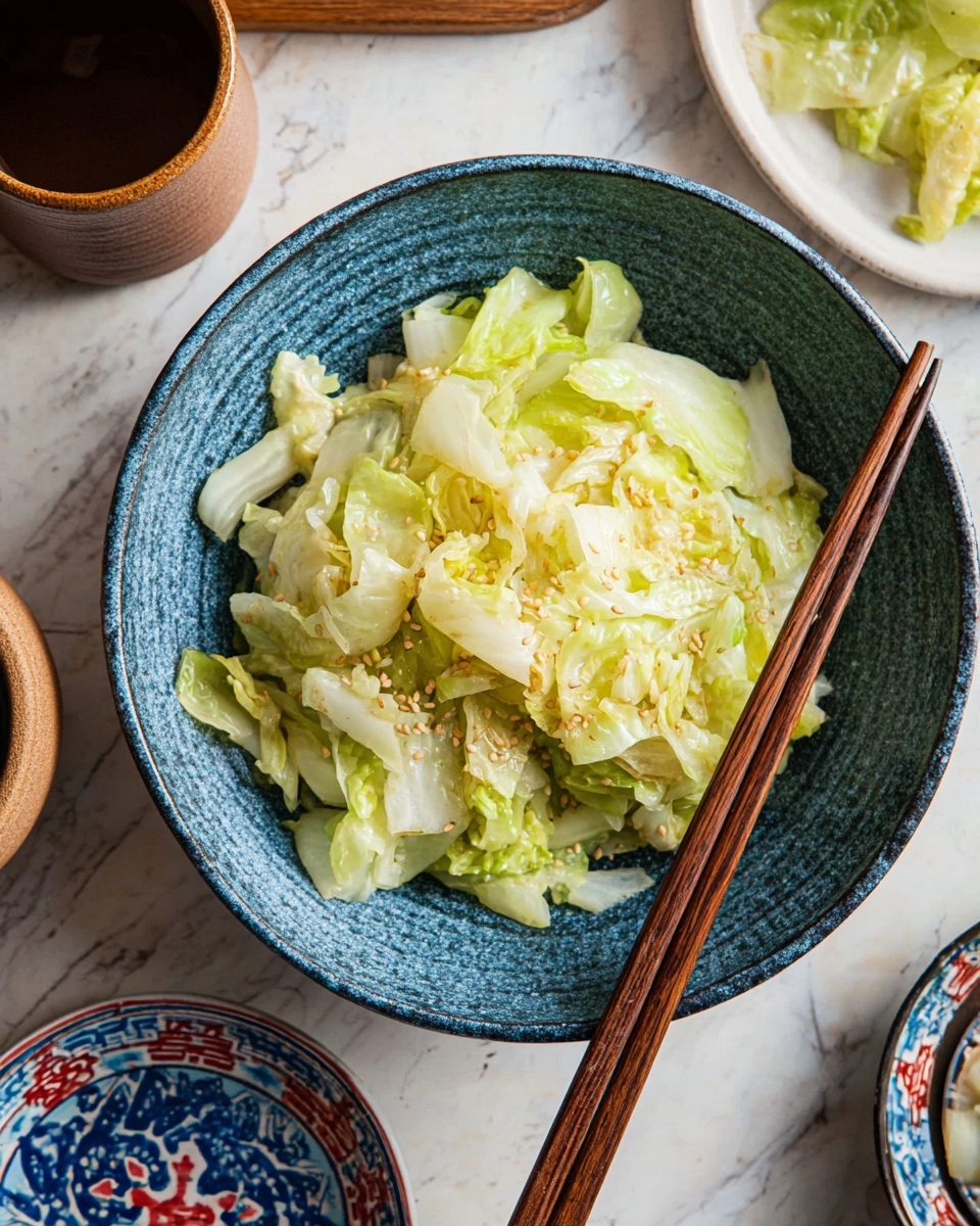 In the image, there is a single-layer dish of chopped light green cabbage with some white parts, topped with small sesame seeds. The cabbage pieces look soft and cooked, placed inside a blue textured bowl. A pair of brown wooden chopsticks rest on the right side of the bowl. The background surface has a white marbled texture, with a small white plate containing more cabbage partially visible on the right and a smaller bowl with a blue and red pattern on the bottom left. Also, a woman's hand is holding a brown cup on the top left photo taken with an iphone --ar 4:5 --v 7