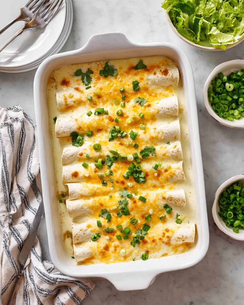 Two rolled tortillas filled with a creamy white sauce and melted cheddar cheese, topped with more white sauce and chopped green onions, sit side by side on a white speckled plate with a brown rim. A dollop of smooth white sour cream rests on top of the tortillas, adding a soft texture. To the left, sliced avocado with a pale yellow-green color and a small pile of fresh green leafy lettuce or spinach are placed neatly on the plate. The plate is set on a smooth white marbled surface. photo taken with an iphone --ar 4:5 --v 7