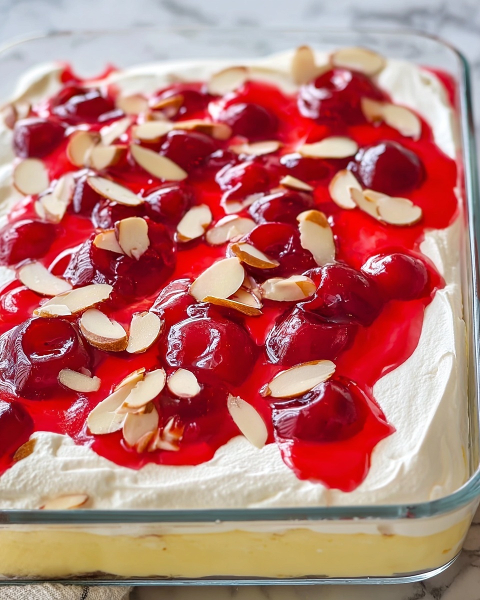 The image shows a dessert in a clear glass rectangular dish with three visible layers: a smooth yellow layer at the bottom, a thick white creamy layer in the middle, and a topping of bright red cherry glaze with whole cherries spread unevenly on the top. Thin, light brown almond slices are scattered over the red glaze, adding texture. The dessert is placed on a white marbled surface with a soft background. photo taken with an iphone --ar 4:5 --v 7