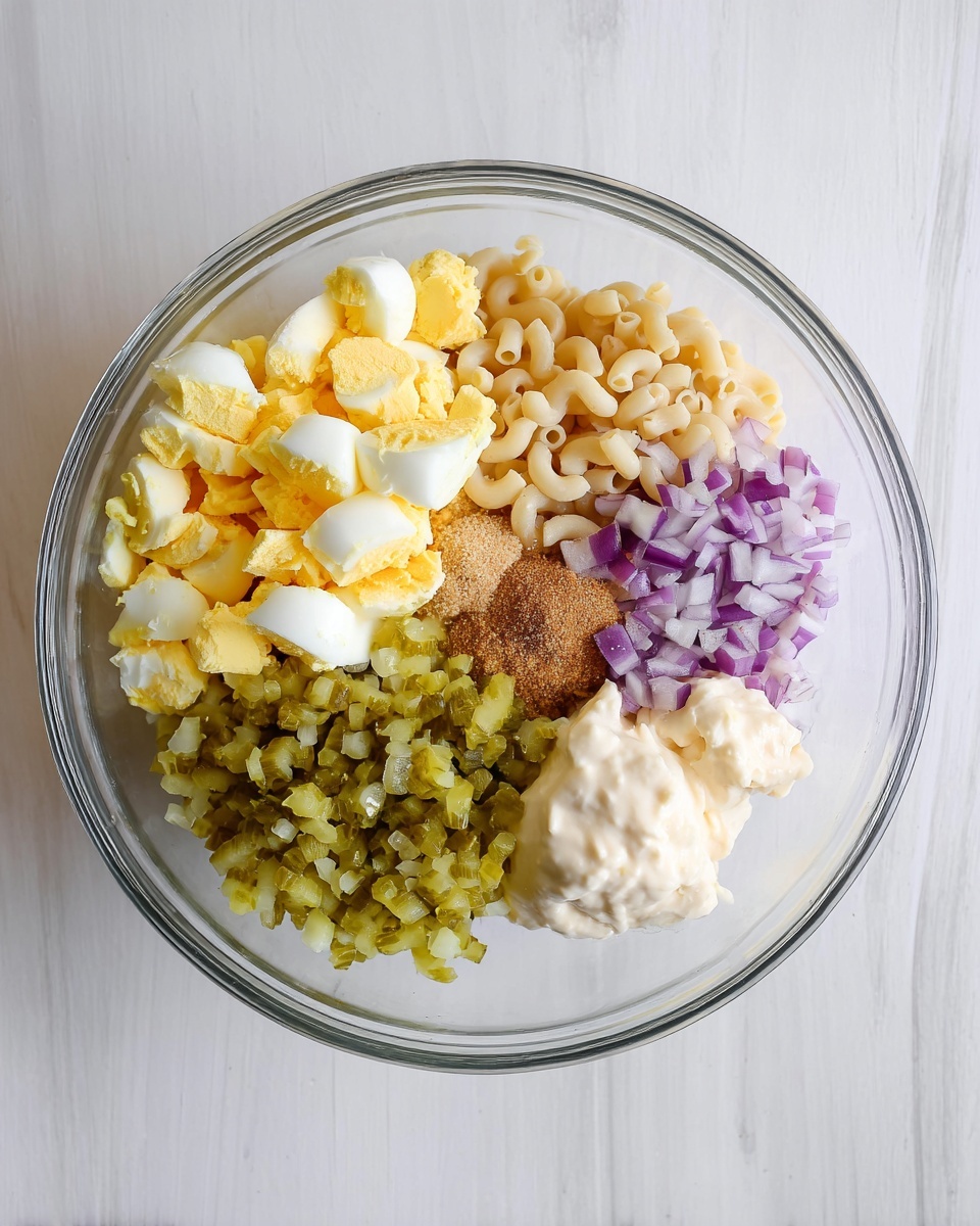 A clear glass bowl is placed on a white marbled surface and holds six distinct layers of ingredients. The largest layer on the left side consists of chopped hard-boiled eggs with bright yellow yolks and white edges. Next to it on the top right is a layer of light beige cooked elbow macaroni pasta. Below the macaroni, finely chopped green pickles are piled up, followed by a layer of finely diced purple onions. At the bottom right is a creamy white mayonnaise-like dollop, smooth and thick in texture. In the center between these layers, there is a small heap of brownish seasoning powder and a small portion of pale yellow mustard. The ingredients are cleanly separated and ready to be mixed. photo taken with an iphone --ar 4:5 --v 7