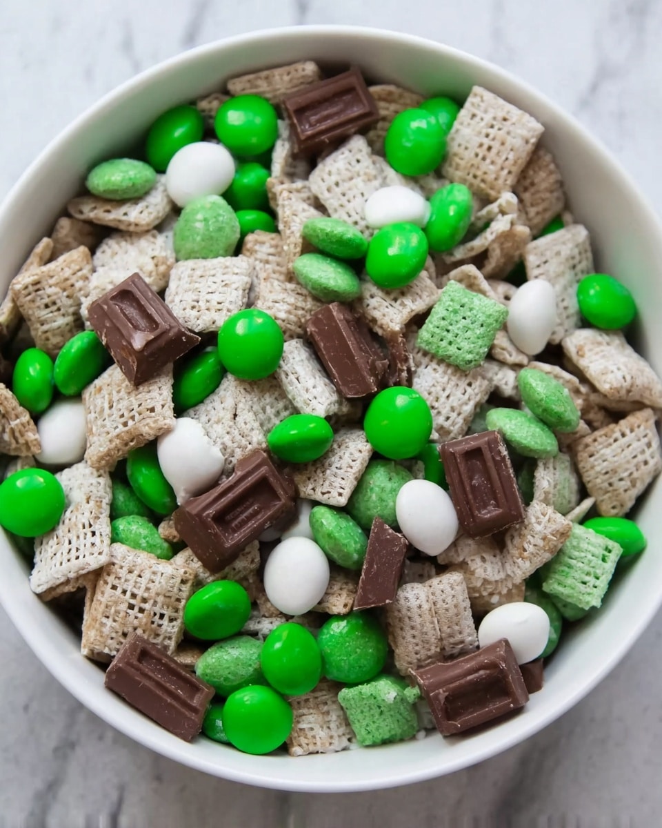 The image shows a white bowl filled with a mixed snack. The snack has three visible layers of different items combined together: white cereal squares with a grainy texture, whole and broken pieces of chocolate squares with a smooth surface and light brown layers, and round candy-coated chocolates in shades of dark green, bright green, and white with a shiny finish. The various colors and textures are spread evenly throughout the bowl, showing a close-up view of the mixture on a white marbled surface. Photo taken with an iphone --ar 4:5 --v 7