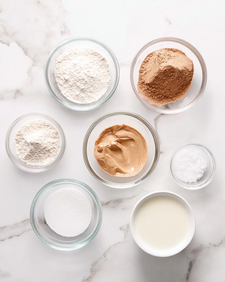 Seven clear glass bowls are arranged on a white marbled surface. From top left to bottom right: a small bowl with a white powder, a medium bowl with brown powder, a medium bowl with light brown creamy paste, a medium bowl with white flour, a small bowl with clear liquid, a small bowl with white granulated sugar, and a white bowl with a small amount of milk. The bowls are evenly spaced and the shot is taken from above, showing the textures and colors clearly. Photo taken with an iphone --ar 4:5 --v 7
