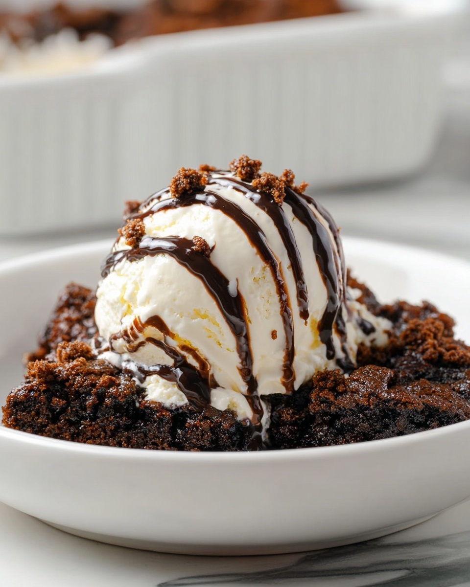 The dish shows a white plate with a base layer of dark brown, crumbly chocolate cake pieces that look moist and rich. On top, there is a single scoop of creamy white vanilla ice cream with a soft, smooth texture. Drizzled over the ice cream is glossy dark chocolate sauce, creating thin stripes. Small chocolate crumbs are sprinkled lightly on the ice cream, adding texture and contrast. The plate is placed on a white marbled surface, and in the background, there's a blurry white ceramic dish. photo taken with an iphone --ar 4:5 --v 7