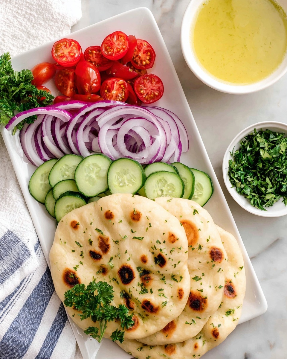 A white rectangular plate features three main layers: bright red cherry tomatoes cut in half clustered on the top left, thin slices of purple onion curved in the middle, and a row of neatly lined green cucumber slices on the bottom right. Fresh green parsley leaves are placed as garnish around the vegetables. In front of the vegetables, two round pieces of flatbread with brown toasted spots and sprinkled herbs lay stacked. To the top right of the plate, there is a small white bowl filled with a light yellow sauce, and another small white bowl containing chopped green herbs. The whole setup is on a white marbled surface with a white and blue striped cloth nearby. Photo taken with an iphone --ar 4:5 --v 7