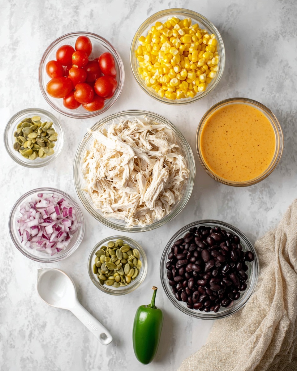 The image shows seven small clear glass bowls on a white marbled surface. The largest bowl in the center is filled with shredded white chicken, surrounded by smaller bowls containing bright yellow corn kernels, creamy orange sauce with a smooth texture, halved red cherry tomatoes, dark black beans, a white measuring cup filled with small diced red onions, and light green pumpkin seeds. A whole green jalapeño pepper lies on the surface near the bowls. A beige cloth is folded at the right edge of the scene. The overall color palette is bright and fresh. Photo taken with an iphone --ar 4:5 --v 7