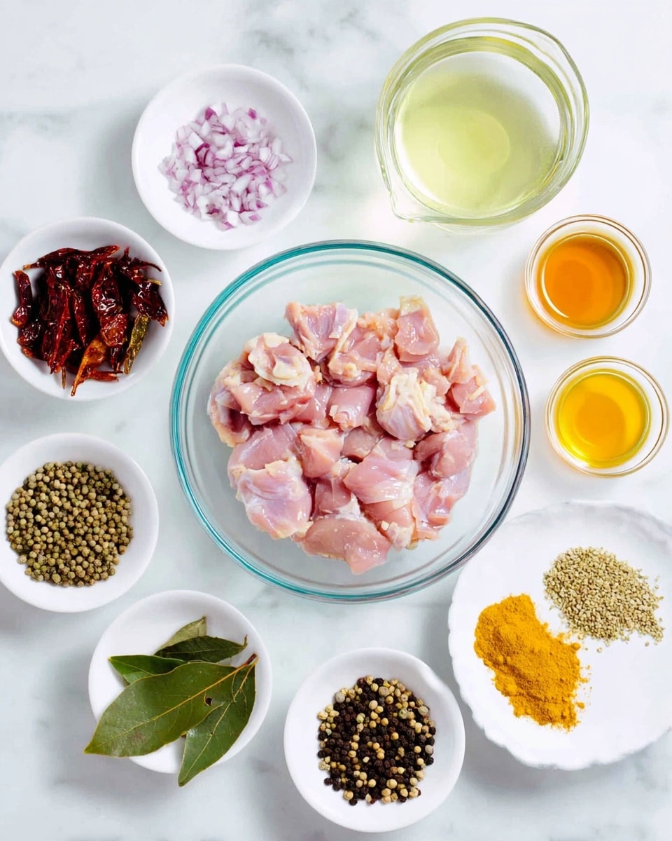 Top view of a white marbled surface holding various small white bowls and a large clear glass bowl in the center filled with raw light pink chicken pieces. Surrounding the bowl from top left moving clockwise: a glass measuring cup with clear water, a small white bowl with chopped garlic, a small clear bowl with a golden liquid, a small clear bowl with another light liquid, a small glass cup of a dark amber liquid, a small white bowl with finely chopped purple onion, a small white bowl with fresh green curry leaves, a small white bowl with a yellow spice powder, a tiny white bowl with white salt, a small white plate with mixed whole spices including black pepper, coriander seeds, fennel seeds, and yellow mustard seeds, and a small white bowl filled with dried red chili peppers. Photo taken with an iphone --ar 4:5 --v 7