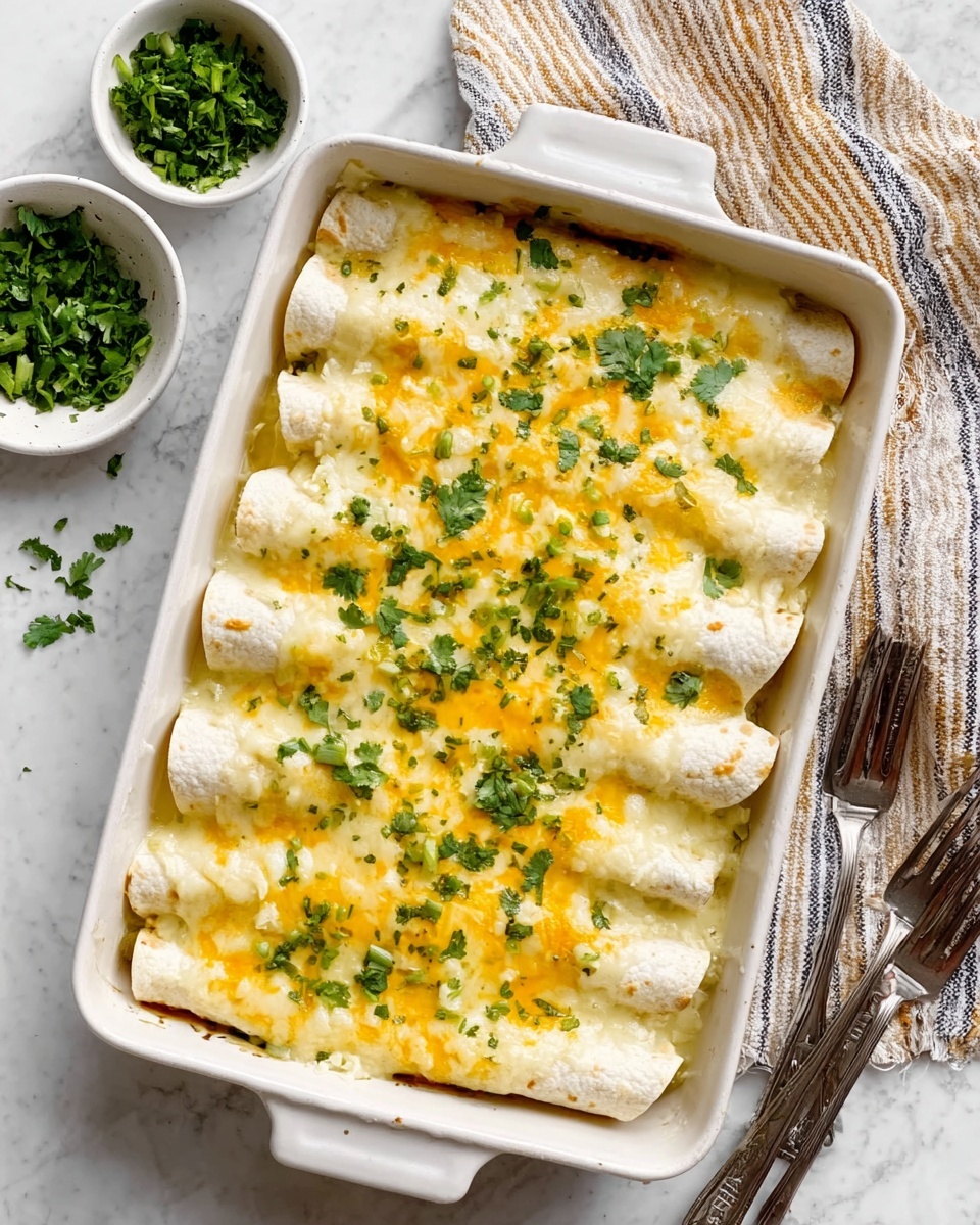 A white rectangular baking dish filled with eight rolled white tortillas covered in melted yellow and white cheese. The cheese is bubbly and creamy, covering the tortillas evenly. The dish is sprinkled with fresh green chopped cilantro all over the top. The baking dish sits on a white marbled surface with a striped cloth napkin near the top right corner. There are small white bowls nearby, one filled with more chopped green herbs. Two forks rest on the surface to the bottom right. Photo taken with an iphone --ar 4:5 --v 7