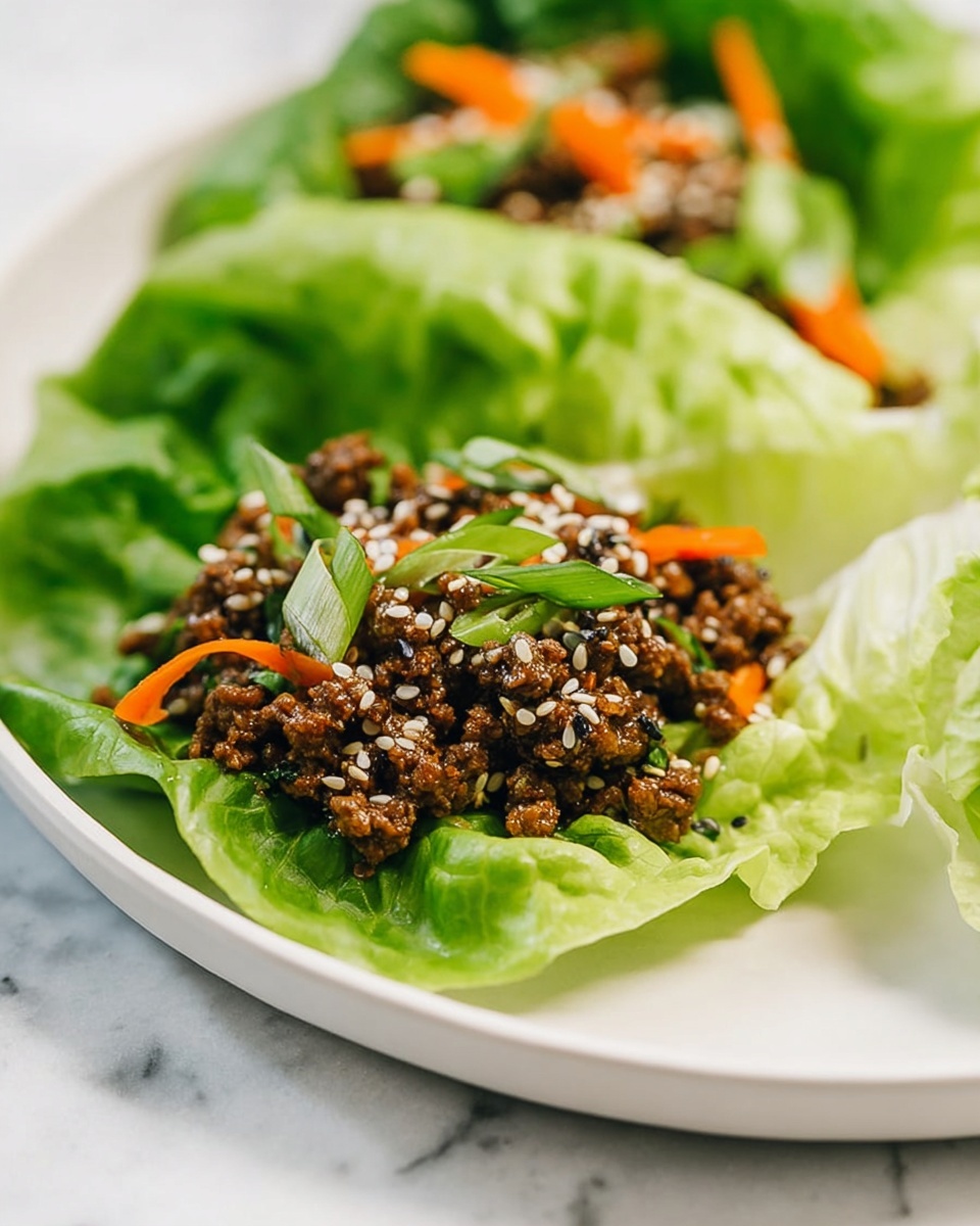 Two lettuce wraps sit on a white plate over a white marbled surface. Each wrap has one large, fresh, green lettuce leaf as the base, slightly curled and crisp in texture. Inside the lettuce, there is a layer of cooked ground meat mixed with small pieces of orange carrot and green scallions. The meat is dark brown with a slightly shiny texture, and the filling is sprinkled with white and black sesame seeds. The colors of the ingredients create a bright contrast between the green lettuce and the warm tones of the filling. photo taken with an iphone --ar 4:5 --v 7
