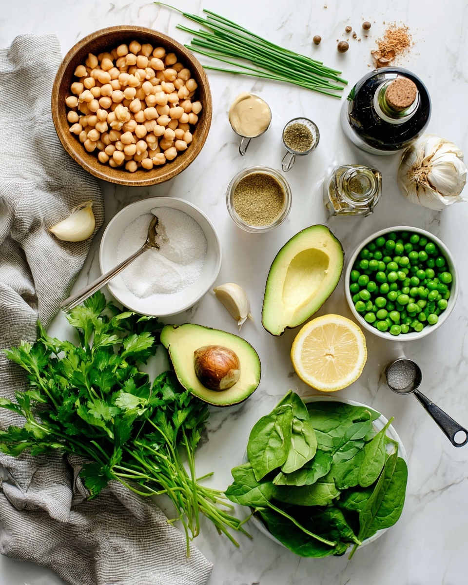 The image shows an overhead view of various fresh ingredients arranged neatly on a white marbled surface. In the center top, there is a small bowl filled with light beige chickpeas. To its right, there is a dark bottle with a cork top and a small open container of ground spices. Below these, thin green chives and green basil leaves are placed vertically. Towards the center bottom, a half avocado with a visible seed and a half avocado without a seed lie side by side. On the left side, a wooden bowl holds white salt, a metal spoon filled with creamy tahini sits on a small white bowl, and a whole lemon with two lemon halves face up next to a bunch of fresh parsley with dark green leaves. Below, a white bowl contains fresh spinach leaves and some fresh cilantro is placed next to it. A small metal measuring cup with bright green peas is near the avocado. A bulb of garlic with some separated cloves is also visible near the herbs. A light gray cloth partially covers the bottom left corner. The scene is well-lit with natural light and shows a clean, fresh preparation setup photo taken with an iphone --ar 4:5 --v 7