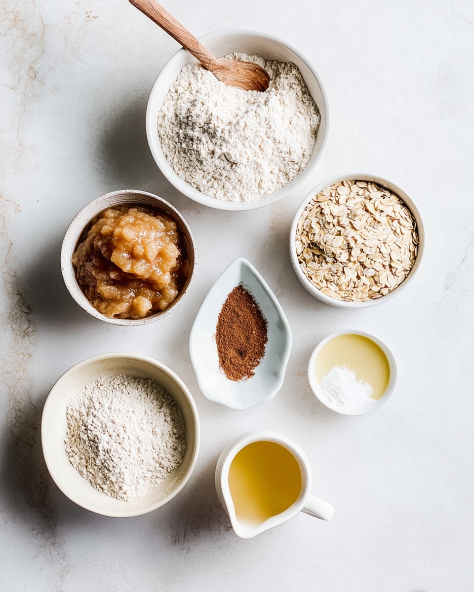 A group of seven white bowls and dishes neatly arranged on a white marbled surface, each holding a different ingredient: a large bowl filled with fine white flour with a wooden spoon inside, a medium bowl with light brown rolled oats, a medium bowl with smooth, light beige applesauce, a small oval dish with dark brown cinnamon powder, a small round bowl with white baking powder, a small pitcher with amber maple syrup, and a tiny cup with pale yellow oil, all viewed from above in soft natural light photo taken with an iphone --ar 4:5 --v 7