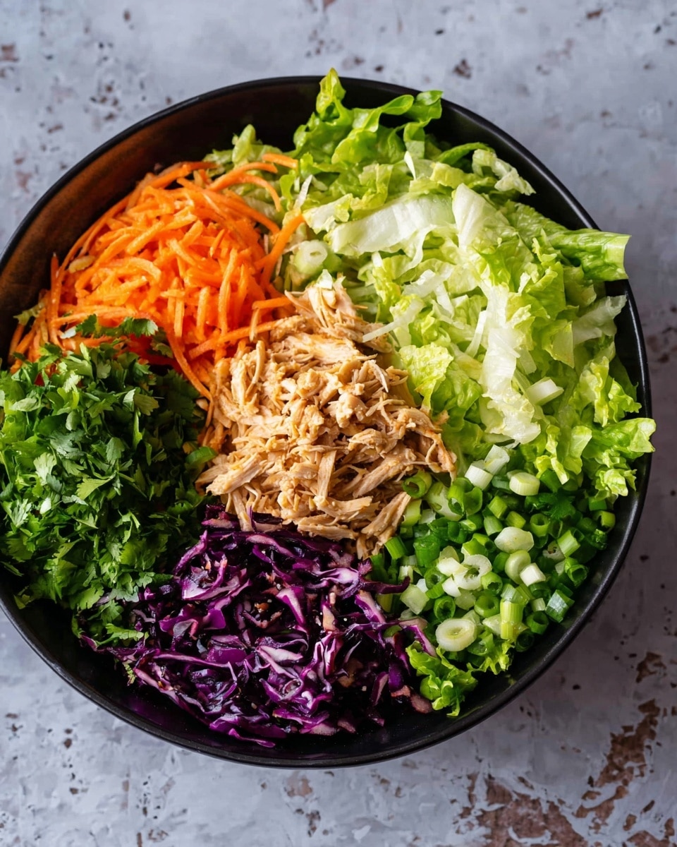 A black bowl on a white marbled texture holds a colorful salad arranged in sections. The center has a layer of light brown shredded cooked chicken. Around it are sections of bright orange shredded carrots, deep purple shredded cabbage, chopped fresh green herbs, white and green chopped spring onions, and two types of green leafy lettuce with different shades and textures. The ingredients are fresh and neatly placed in a circle inside the bowl. photo taken with an iphone --ar 4:5 --v 7