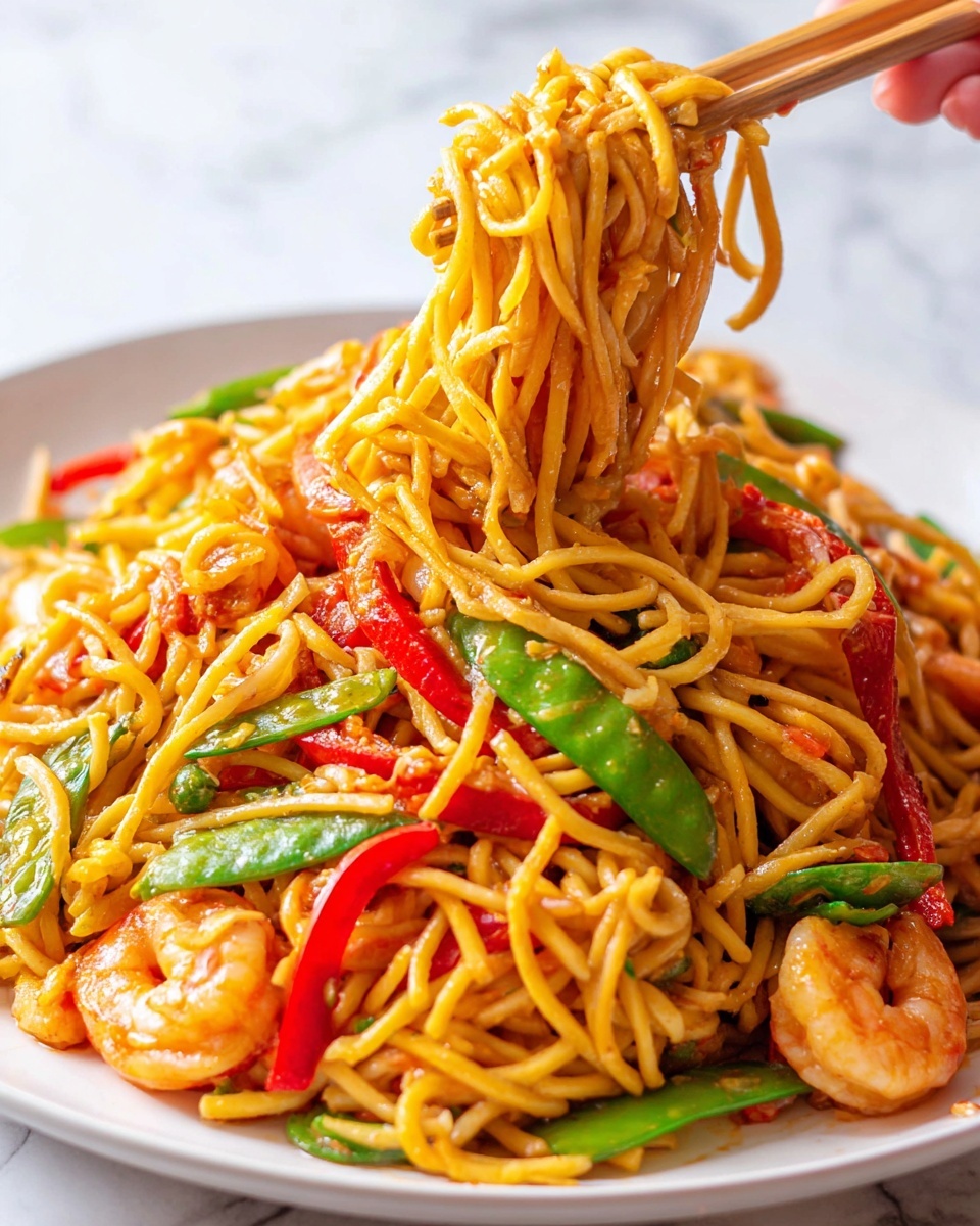 The image shows a close-up of a white plate filled with stir-fried noodles mixed with bright red bell pepper slices, green snap peas, and small cooked shrimp that have a slight pink color. The noodles are golden yellow and glistening with sauce, creating a shiny texture. A pair of wooden chopsticks held by a woman's hand is lifting a bunch of noodles mixed with red pepper strips from the plate. The background is a white marbled surface, and the scene is well-lit with natural light highlighting the glossy and colorful ingredients. photo taken with an iphone --ar 4:5 --v 7