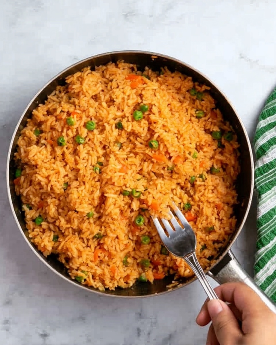 The image shows a top view of a black pan filled with orange-colored rice mixed with small pieces of green peas and carrots, giving the dish a colorful look. A woman's hand is holding a fork, ready to scoop some rice. The pan is placed on a white marbled surface, and a green and white striped cloth napkin is partially visible in the top right corner. Photo taken with an iphone --ar 4:5 --v 7
