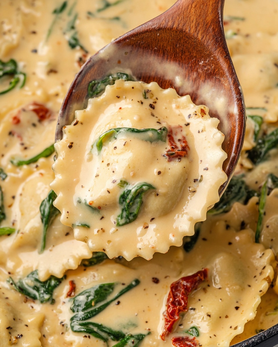 The image shows a close-up of creamy ravioli pasta in a thick, light beige sauce with visible herbs and pepper specks. The ravioli have a scalloped edge and are coated evenly in the sauce, which looks smooth and rich. Bright green spinach leaves and pieces of red sun-dried tomatoes are mixed into the sauce, adding color contrast. A wooden spoon is scooping up the ravioli and sauce from a white marbled surface, capturing a spoonful with a sun-dried tomato and some spinach. The texture looks soft and creamy, with the pasta appearing tender. photo taken with an iphone --ar 4:5 --v 7