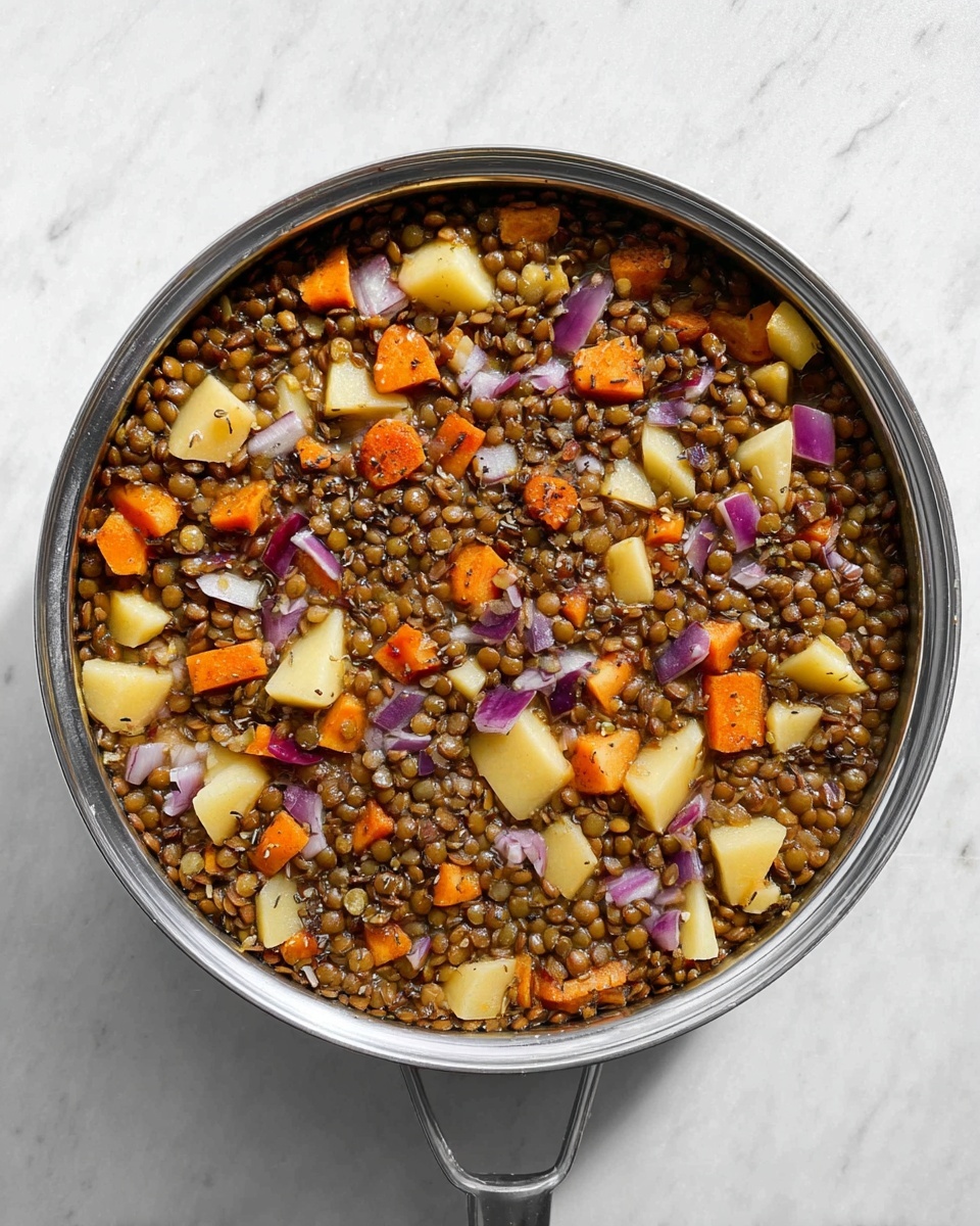 A round metal pan filled with cooked lentils covering most of the surface, mixed with orange carrot chunks, pale yellow potato pieces, and small purple onion segments scattered evenly throughout; the lentils have a soft, slightly shiny texture, while the vegetables add varied shapes and colors standing out against the lentils. The pan is placed on a white marbled surface with a clean look. Photo taken with an iphone --ar 4:5 --v 7