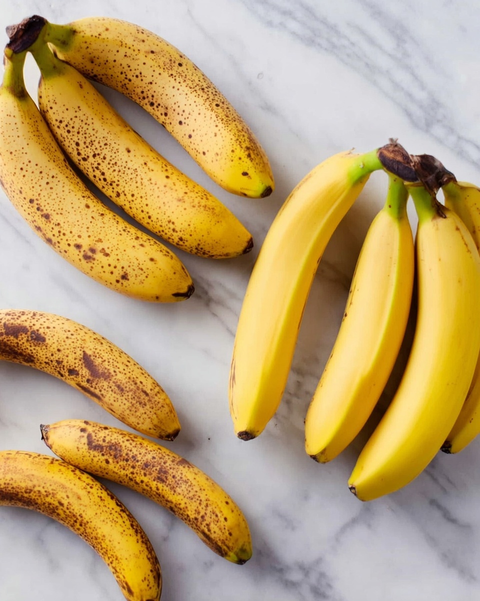 Banana Mochi with Coconut Flakes Recipe 4 The image shows four groups of bananas placed on a white marbled surface. The group on the left has three bananas with yellow peel and brown spots, showing they are ripe. Next to it is a smaller group of two bananas with darker brown spots and more browning on the peel. To the right is another group of two bananas with lighter yellow peel and fewer brown spots, appearing less ripe. Lastly, on the far right, a bunch of four bananas with mostly bright yellow peel and green stems is visible, showing they are the freshest. The bananas have a smooth texture with some brown freckles on the skin. photo taken with an iphone --ar 4:5 --v 7