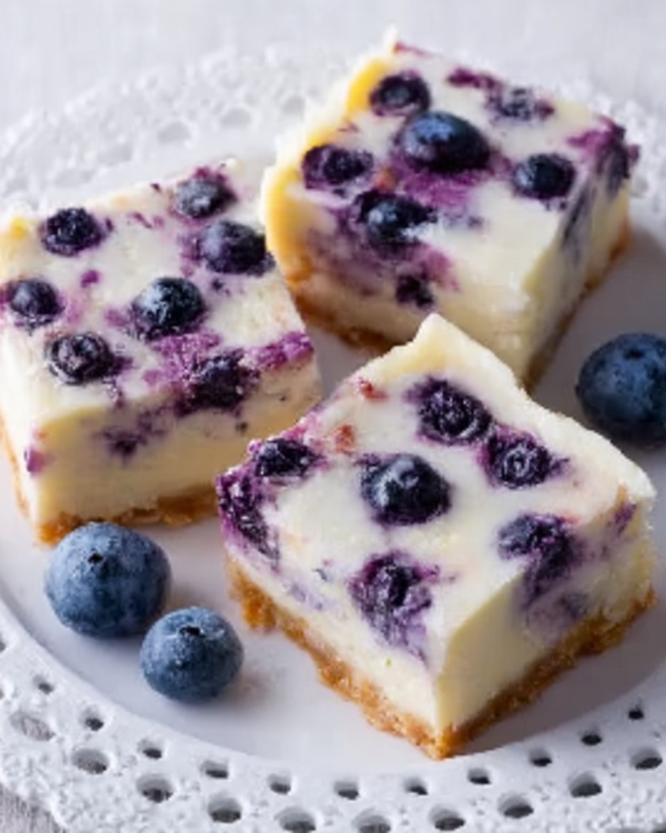 The image shows three square pieces of a dessert with a light creamy layer on top and purple blueberries baked inside and on top. Each piece is placed on a white lace-edged plate with small holes around the edge. The dessert has smooth creamy white tops with scattered blueberries, and the inside looks soft with a mix of white and purple colors. A few loose blueberries are on the plate near the dessert pieces. The overall look is fresh and sweet. photo taken with an iphone --ar 4:5 --v 7