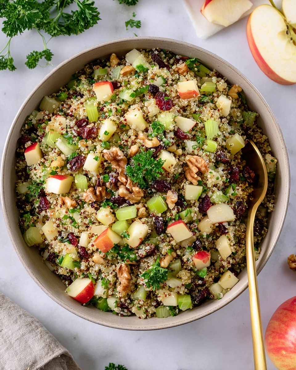 A round bowl filled with a colorful quinoa salad that has three main layers mixed together: small round grains of beige and white quinoa, bright green diced celery pieces, and small cubes of red and pale yellow apple skin and flesh, along with dark red dried cranberries and light brown walnut chunks scattered on top. Fresh green parsley leaves are mixed throughout, adding a fresh touch. A gold spoon rests inside the bowl on the right side, partially buried in the salad. The bowl sits on a white marbled surface with some parsley leaves and an apple sliced in the background. photo taken with an iphone --ar 4:5 --v 7