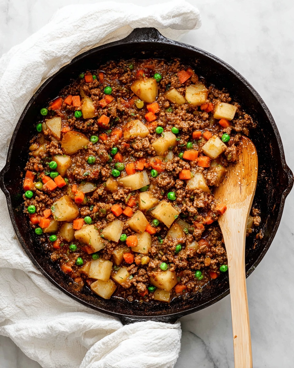 A black cast iron pan filled with cooked ground meat mixed with small pieces of orange carrot, green peas, and cubed light beige potatoes, all coated in a rich brown sauce. A wooden spoon rests inside the pan, touching the mixture and positioned diagonally from the top right toward the center. The pan sits on a white marbled surface with a white cloth draped under its handle. Photo taken with an iphone --ar 4:5 --v 7