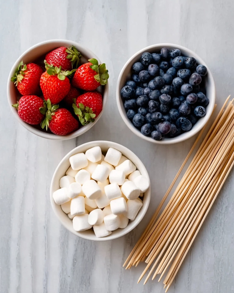 The image shows three small white bowls arranged on a white marbled surface. The bowl on the left is filled with bright red strawberries with green leaves. The bowl in the middle holds small white marshmallows, and the one on the right is full of plump, dark blue blueberries. To the right of the bowls is a neat stack of wooden skewers lying on the surface. photo taken with an iphone --ar 4:5 --v 7