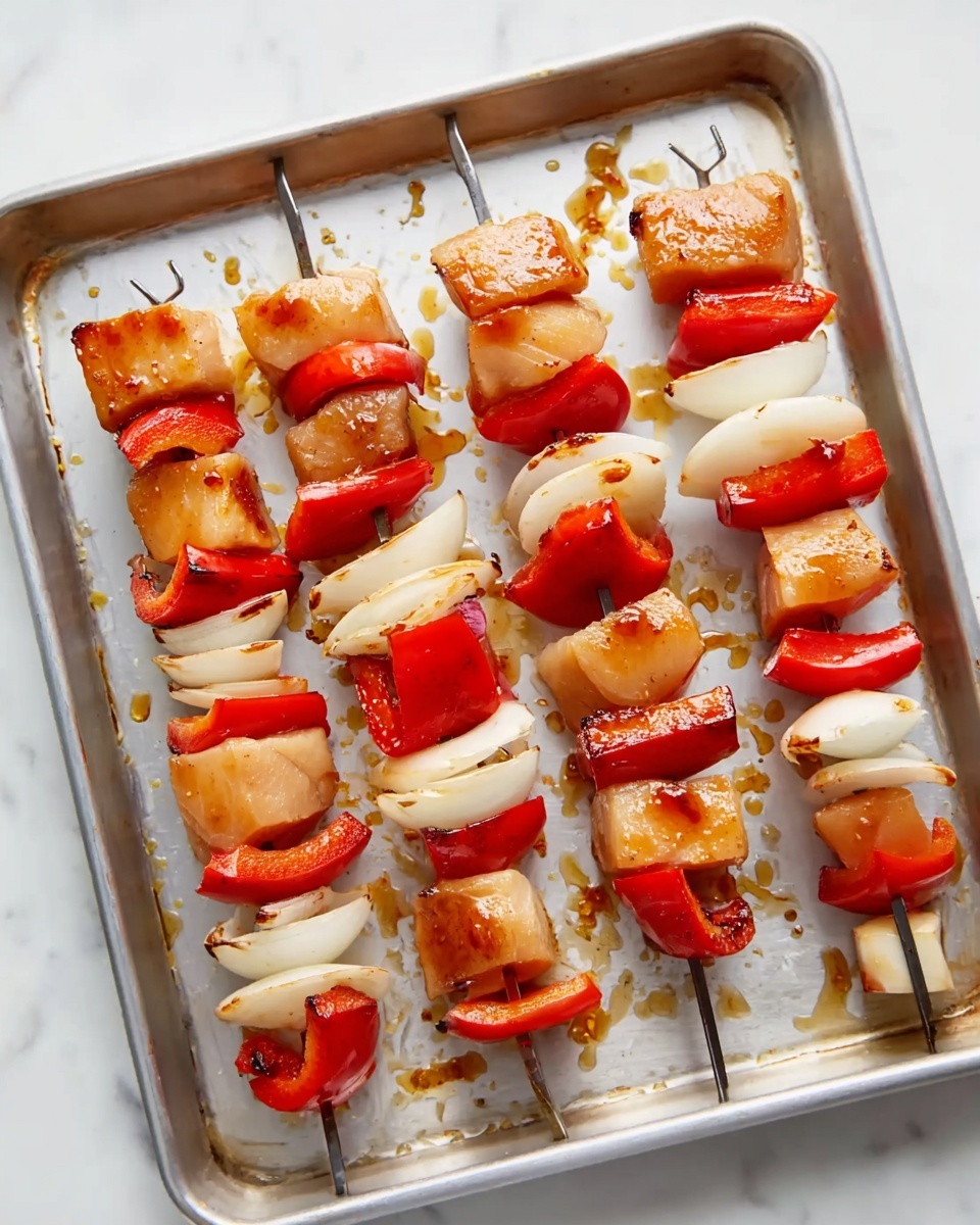 Yummy Honey Chicken Kabobs Recipe 4 The image shows six metal skewers arranged on a rectangular silver tray, each holding layers of cubed raw light brown chicken, white thick onion slices, and bright red bell pepper pieces. The chicken blocks are shiny and marinated, alternating with the slightly curved onion segments and the smooth, glossy red pepper sections. The tray has scattered spots of marinade around the skewers and a white marbled surface underneath with soft lighting highlighting the fresh ingredients photo taken with an iphone --ar 4:5 --v 7