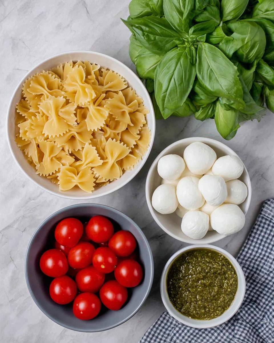 The image shows four white bowls arranged closely on a white marbled surface. The largest bowl on the left is filled with uncooked farfalle pasta, showing a light yellow color with a smooth texture. To the right, there is a bunch of fresh green basil leaves with visible veins and a slightly shiny texture. Below the basil, a medium white bowl holds several small, smooth, and round white mozzarella balls. On the bottom left, another white bowl is filled with bright red cherry tomatoes that have a glossy surface. Lastly, in the bottom right corner, a small white bowl contains a thick, coarse green pesto sauce. Photo taken with an iphone --ar 4:5 --v 7