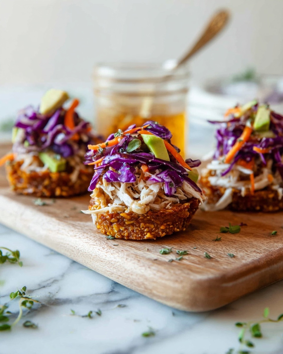 The image shows three small stacks of food on a wooden board over a white marbled surface. Each stack has three layers: the bottom layer is a crispy, golden-brown base with a rough texture; the middle layer is white shredded pieces that look soft and moist; the top layer is made up of bright purple cabbage leaves mixed with thin orange carrot strips and small green avocado chunks, all coated with a light cream sauce. In the background, there is a clear glass jar with a spoon inside, filled with a golden liquid, and some green herbs scattered around the board and surface. The photo taken with an iphone --ar 4:5 --v 7