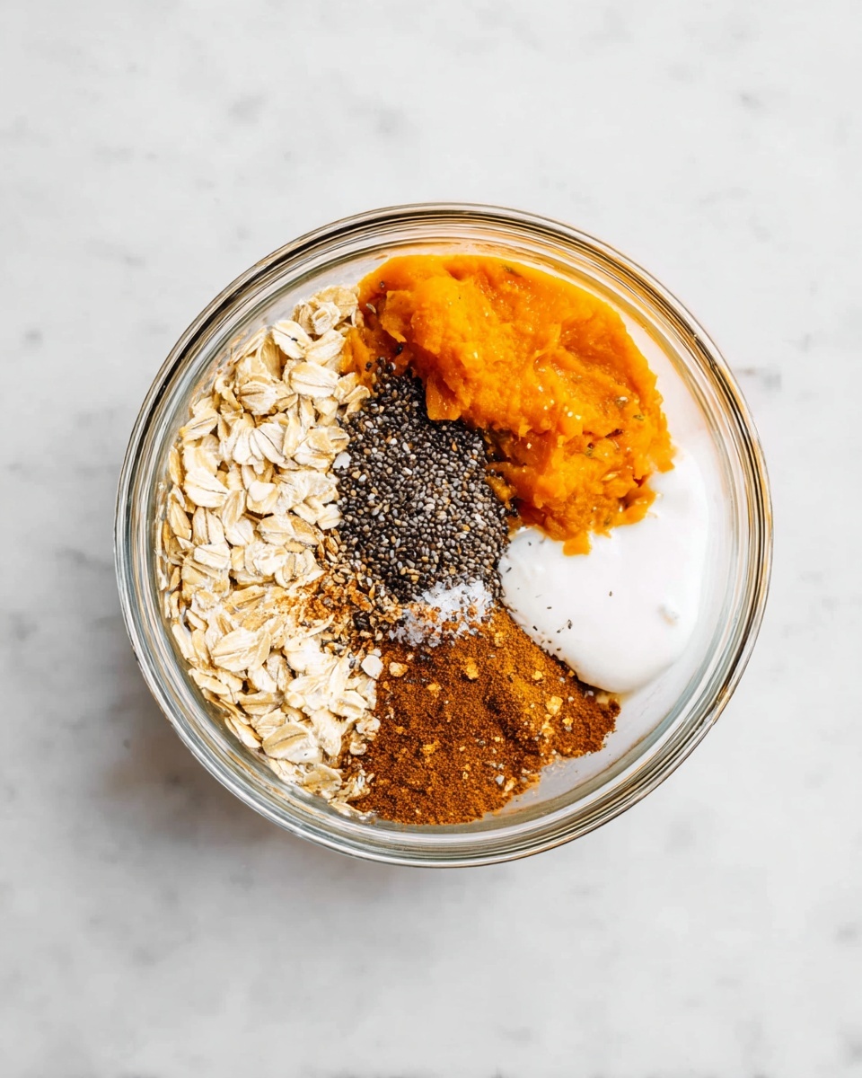 A clear glass bowl is placed on a white marbled surface, showing six distinct ingredients next to each other without mixing. Starting from the bottom left and moving clockwise, there is a cluster of light beige rolled oats with a dry texture, above it is a pile of small black chia seeds with a shiny surface, next to the seeds is a bright orange smooth pumpkin puree, topped slightly with a small mound of white coarse salt. To the right of the salt is a warm brown heap of ground cinnamon with a powdery texture, and below it is a dollop of white creamy coconut oil. The ingredients create a colorful, segmented circle inside the bowl. Photo taken with an iphone --ar 4:5 --v 7