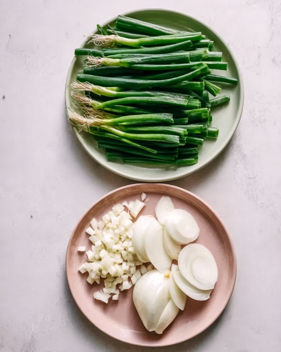 Two white plates are set on a white marbled surface, one above the other. The top plate holds chopped green onions, arranged in two neat groups with long green stalks pointing in one direction and lighter green parts below. The bottom plate contains small white garlic pieces on the left side and smooth, white onion slices on the right side, both appearing fresh and clean. Photo taken with an iphone --ar 4:5 --v 7