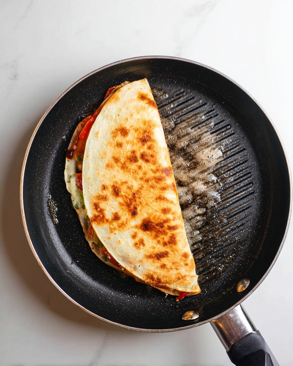 The image shows a toasted folded tortilla in a black grill pan, sitting on a white marbled surface. The tortilla is golden brown with darker spots and grill marks from the pan. Inside the folded tortilla, you can see layers of ingredients slightly peeking out, including red, green, and orange colors suggesting cooked veggies or sauce. The pan has some melted butter or oil with bubbles around the edges of the tortilla, adding shine and texture. The handle is visible at the bottom right corner. photo taken with an iphone --ar 4:5 --v 7