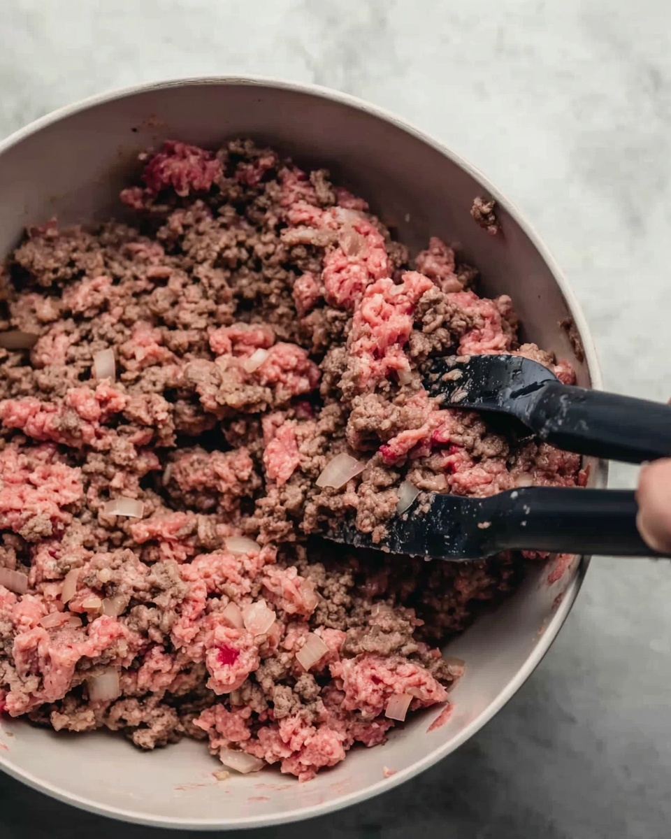 The image shows a close-up of cooked ground meat with some parts still pink and others browned. The meat has a crumbly texture with small chunks and some pieces of onion mixed in. Two black kitchen spatulas are placed inside the white bowl holding the meat, with one spatula partially lifted by a woman's hand. The bowl sits on a white marbled surface. Photo taken with an iphone --ar 4:5 --v 7
