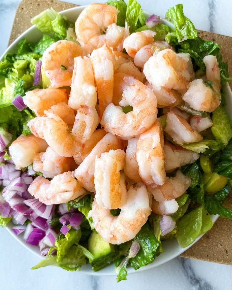 A white plate holds a fresh salad with three visible layers: the bottom layer is chopped green lettuce, followed by a layer of diced purple onion, then topped with a generous pile of cooked shrimp with light pink and white colors. The shrimp pieces are spread evenly across the salad, showing a slightly shiny texture. The background is a white marbled surface. Photo taken with an iphone --ar 4:5 --v 7