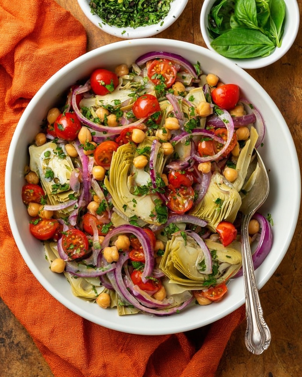 A white bowl filled with a colorful salad showing layers of light green artichoke heart wedges placed on top, bright red halved cherry tomatoes scattered throughout, thin rings of purple-red onion spread around, and small round beige chickpeas mixed in. Fresh green chopped herbs sprinkle the salad. A silver spoon rests inside the bowl on the right side. The bowl sits on a wooden surface next to an orange cloth, with two small white bowls nearby, one filled with chopped green herbs and another with fresh green basil leaves. photo taken with an iphone --ar 4:5 --v 7