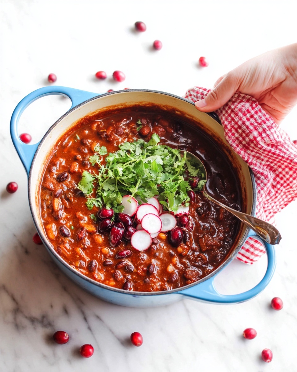 A blue pot on a white marbled surface holds a thick reddish-brown stew with visible beans and vegetables mixed in. On top, there is a small pile of fresh green cilantro leaves, dark red cranberries scattered around, and three thin, round slices of white and red radish arranged neatly. A silver spoon is partially dipped in the stew on the right side, and a woman's hand holding the pot's handle wrapped with a red and white checkered towel is on the upper right. More cranberries are scattered around the pot on the surface. photo taken with an iphone --ar 4:5 --v 7
