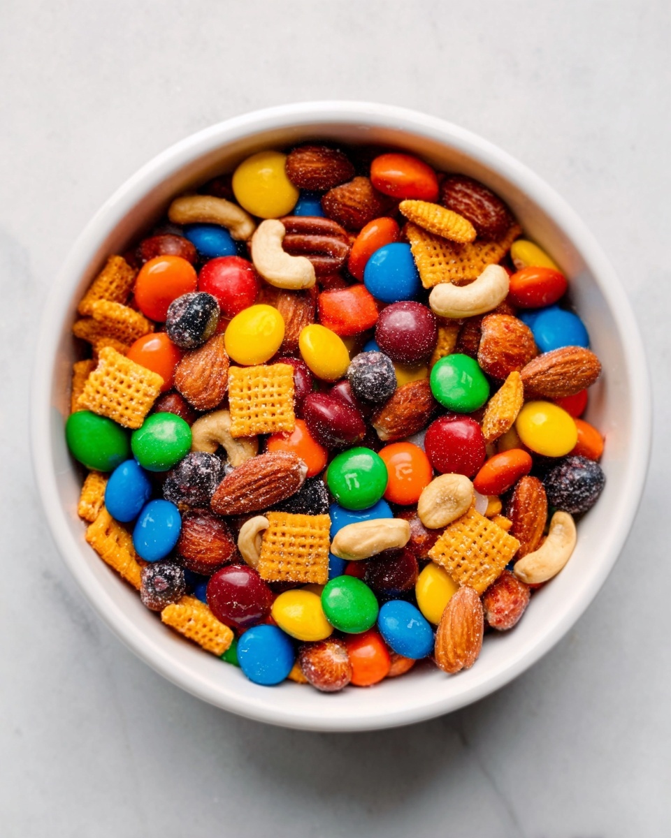 A white bowl full of colorful trail mix that includes red, yellow, blue, and green candy pieces, brown and white nuts, and dark chocolate chips. The bowl is sitting on a white marbled surface with some of the trail mix spilled around the bowl, showing the variety of colors and textures. The image is bright and clear, capturing the mix's vibrant and crunchy look. photo taken with an iphone --ar 4:5 --v 7