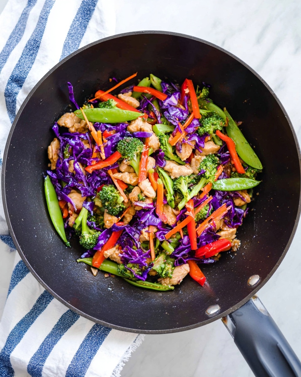 A black wok filled with stir-fry showing multiple layers: at the bottom, small pieces of cooked light brown chicken, above that bright green broccoli florets and snap peas, scattered with thin orange carrot sticks, red bell pepper strips, and bright purple cabbage shreds. The wok is placed on a surface with white marbled texture and a white and blue striped cloth nearby. Photo taken with an iphone --ar 4:5 --v 7