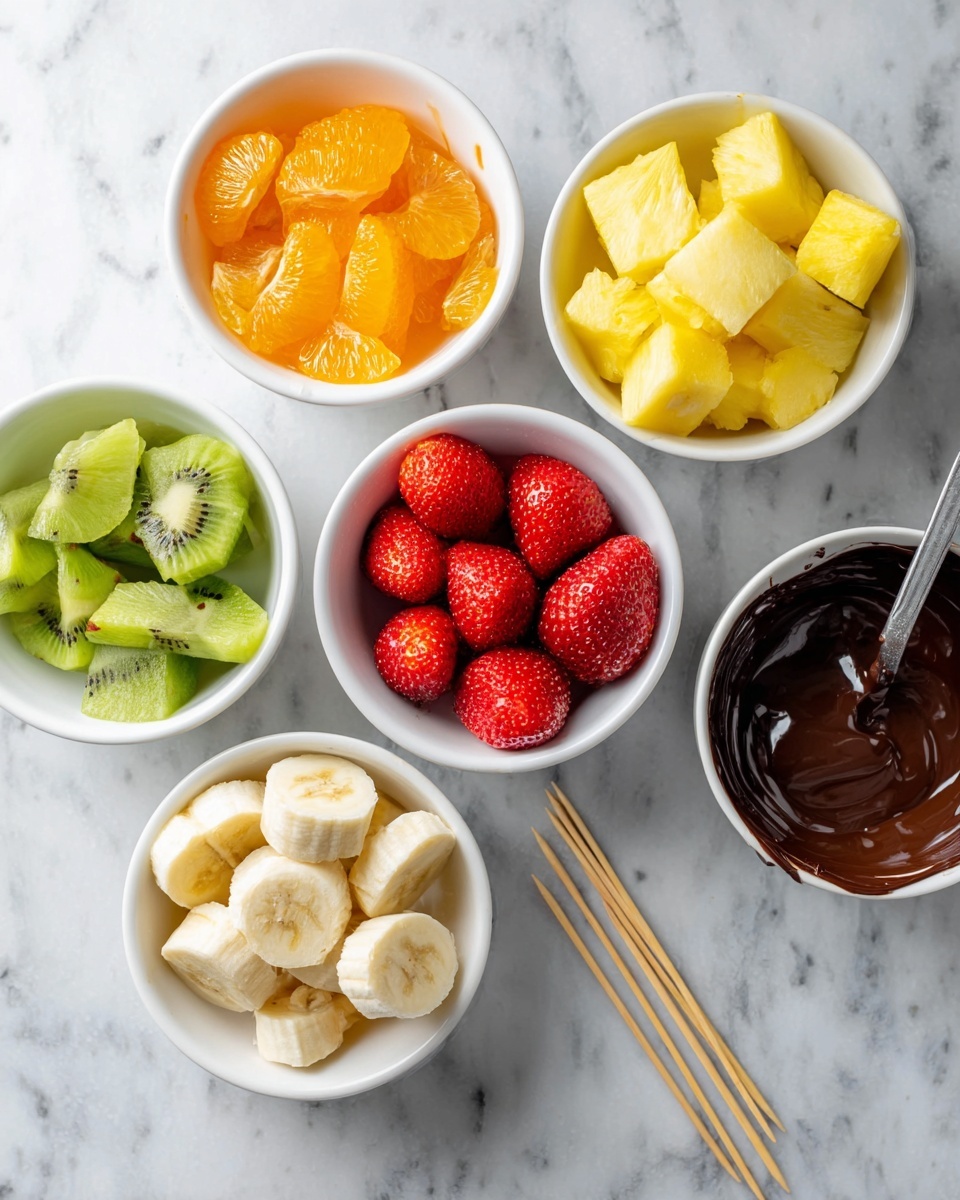 Rainbow Fruit Skewers with Dark Chocolate Drizzle Recipe 4 The image shows five white bowls arranged on a white marbled surface. The top right bowl holds bright yellow pineapple chunks with a slightly rough texture. The top left bowl contains orange segments with a juicy and glossy look. The center bowl is filled with six red strawberries, smooth and shiny, arranged in a single layer. The bottom left bowl has green kiwi pieces, cut into chunks with visible black seeds inside. The bottom center bowl has banana slices that are pale yellow with a soft, smooth texture. On the bottom right, a white bowl contains dark melted chocolate with a shiny surface, and a small silver spoon resting inside. Wooden skewers lie on the surface near the orange segments. photo taken with an iphone --ar 4:5 --v 7