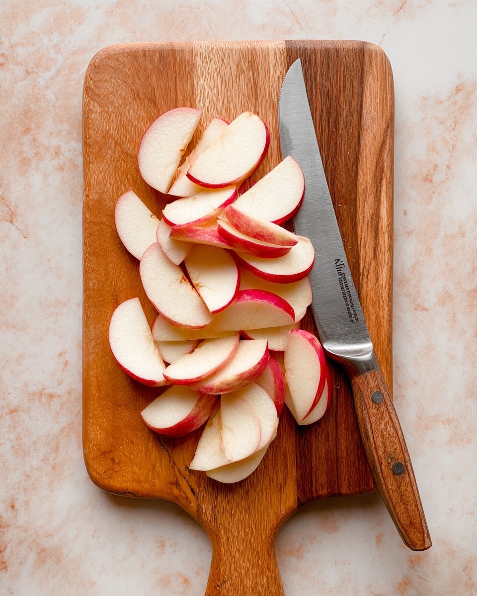 A wooden board with a handle holds about twenty thin slices of red apple arranged loosely in the middle, showing white flesh with bright red skin edges. A clean silver knife with a wooden handle lies diagonally on the right side of the board, its blade pointing up and slightly to the left. The background is a white marbled surface. photo taken with an iphone --ar 4:5 --v 7