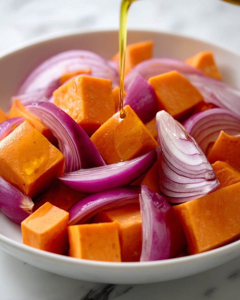 The image shows a close-up of large, bright orange cubes of sweet potato and thick slices of purple-red onion placed closely together in a white dish. The cubes are smooth and shiny, giving a fresh and firm texture, while the onion slices have a layered, translucent appearance. A thin stream of golden oil is being poured over the vegetables, adding a glossy finish and highlighting the rich, warm colors. The scene is set on a white marbled surface. photo taken with an iphone --ar 4:5 --v 7