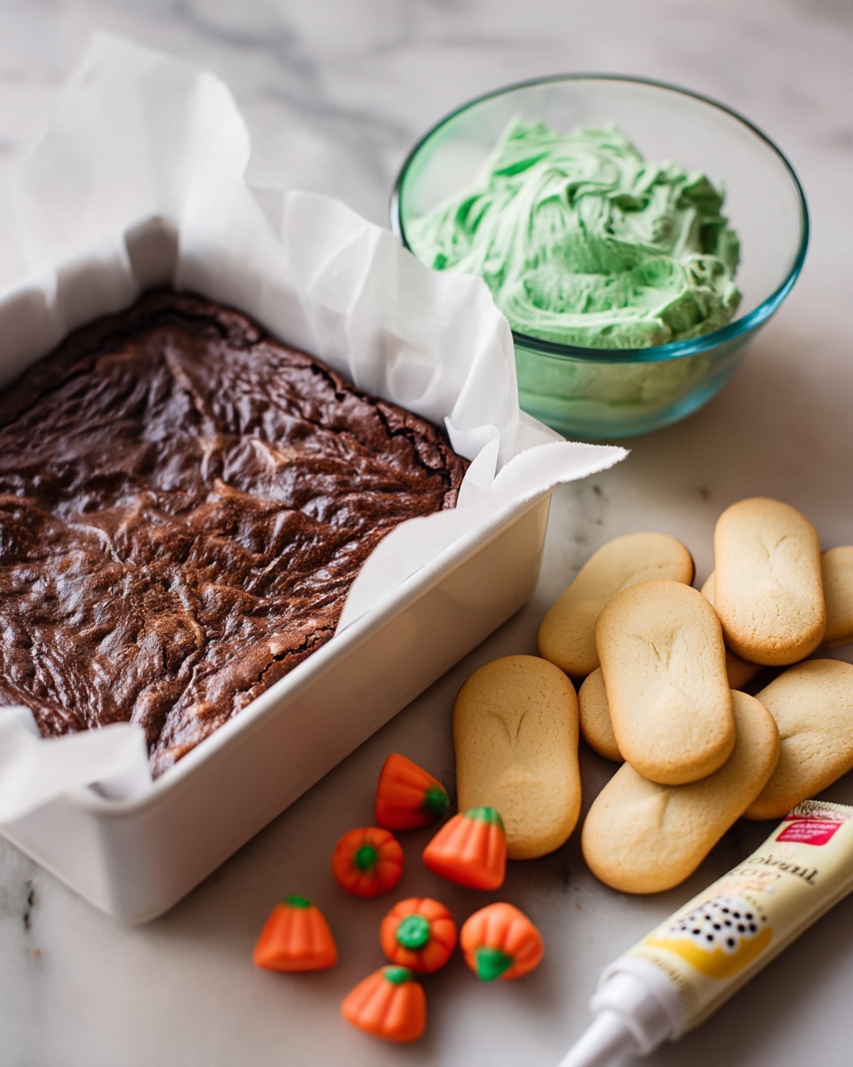 A dark brown baked brownie layer with a slightly rough texture sits in a square pan lined with white parchment paper on a white marbled surface; next to it are bright orange pumpkin-shaped candies with green tops scattered near a small tube of white writing gel with pink label details; beside these, a clear white bowl holds a swirled light green frosting with a fluffy texture, and a small stack of pale yellow oval-shaped cookies with smooth surfaces rests nearby, all arranged neatly. photo taken with an iphone --ar 4:5 --v 7