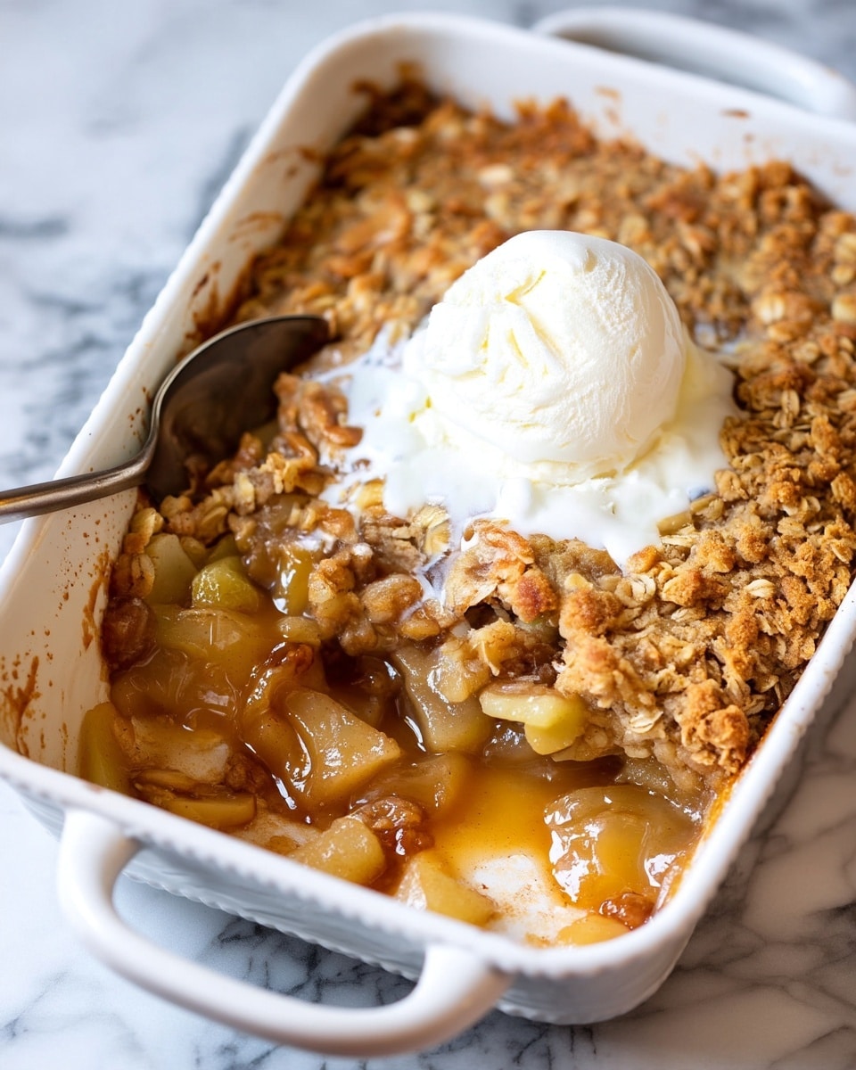 A white bowl filled with a base layer of soft, cooked apple chunks coated in a light brown syrupy sauce, topped with a crumbly oat and nut mixture that adds texture; in the center sits a single scoop of white vanilla ice cream with smooth, melting edges, over which a sticky golden caramel sauce is being drizzled from a spoon held above, the caramel flowing down the ice cream in thick ribbons. The scene is set on a white marbled surface with colorful apples around the bowl, creating a warm cozy feeling. Photo taken with an iphone --ar 4:5 --v 7