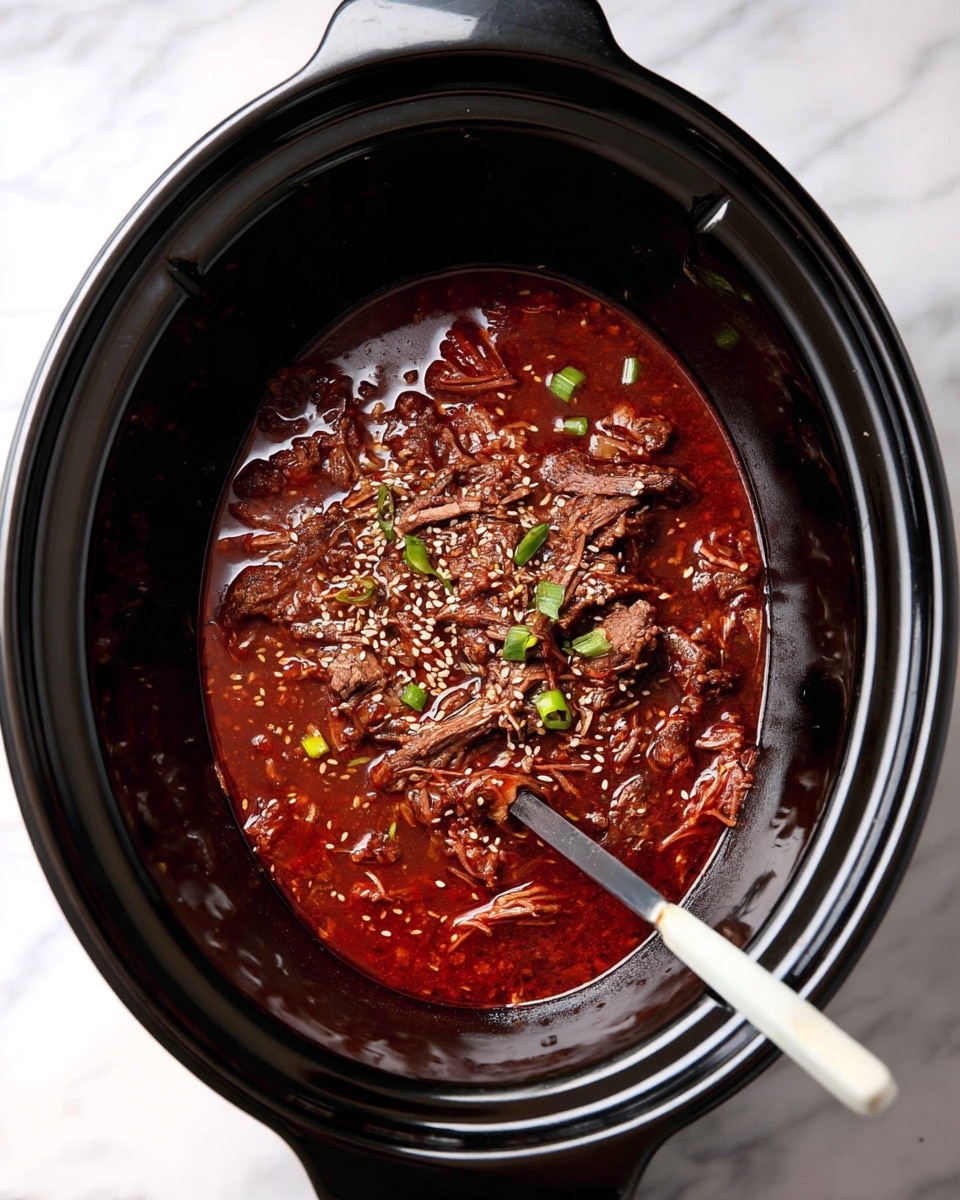 Inside a slow cooker, there is one main layer of dark brown shredded meat soaked in a thick red sauce with oily highlights. The meat is sprinkled with white sesame seeds and small green onion pieces scattered on top. Two white-handled utensils rest inside, one on each side of the cooker, slightly touching the sauce. The slow cooker is black and glossy, set against a white marbled surface. photo taken with an iphone --ar 4:5 --v 7