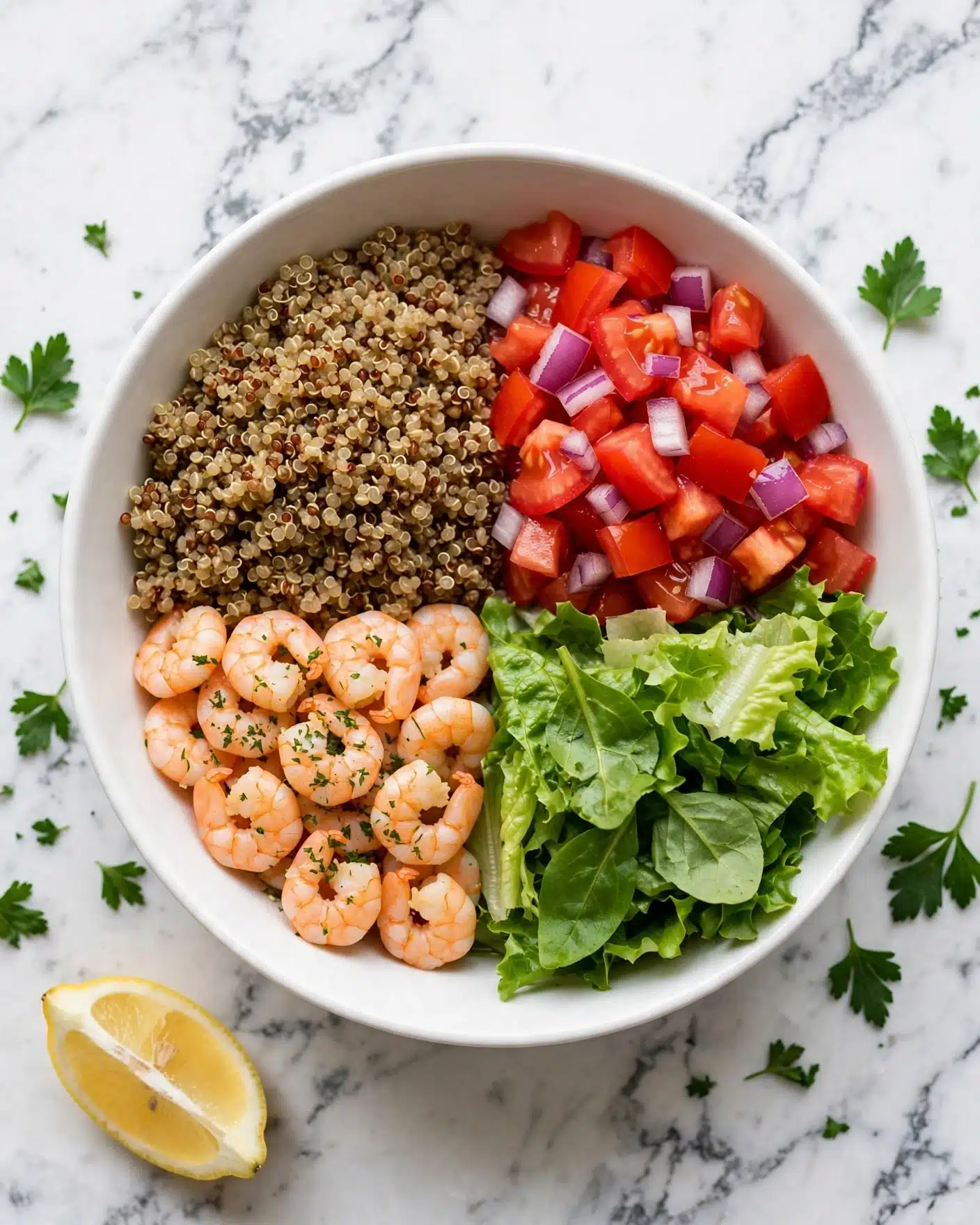 Lemon-Chili Shrimp Avocado Quinoa Bowls Recipe 5 A white bowl contains a layered meal with quinoa as the base layer in the center, showing a grainy texture and light brown color. On the left side of the quinoa are cooked shrimp, light pink and slightly shiny. On the right side, bright green lettuce leaves add a fresh texture, and near the top right, there are two slices of light green avocado. Above the quinoa, there are small piles of chopped red tomatoes and finely diced purple onions. A woman's hand holds a spoon hovering over the bowl. The bowl is placed on a white marbled surface with lemon wedges and scattered fresh parsley visible nearby. photo taken with an iphone --ar 4:5 --v 7