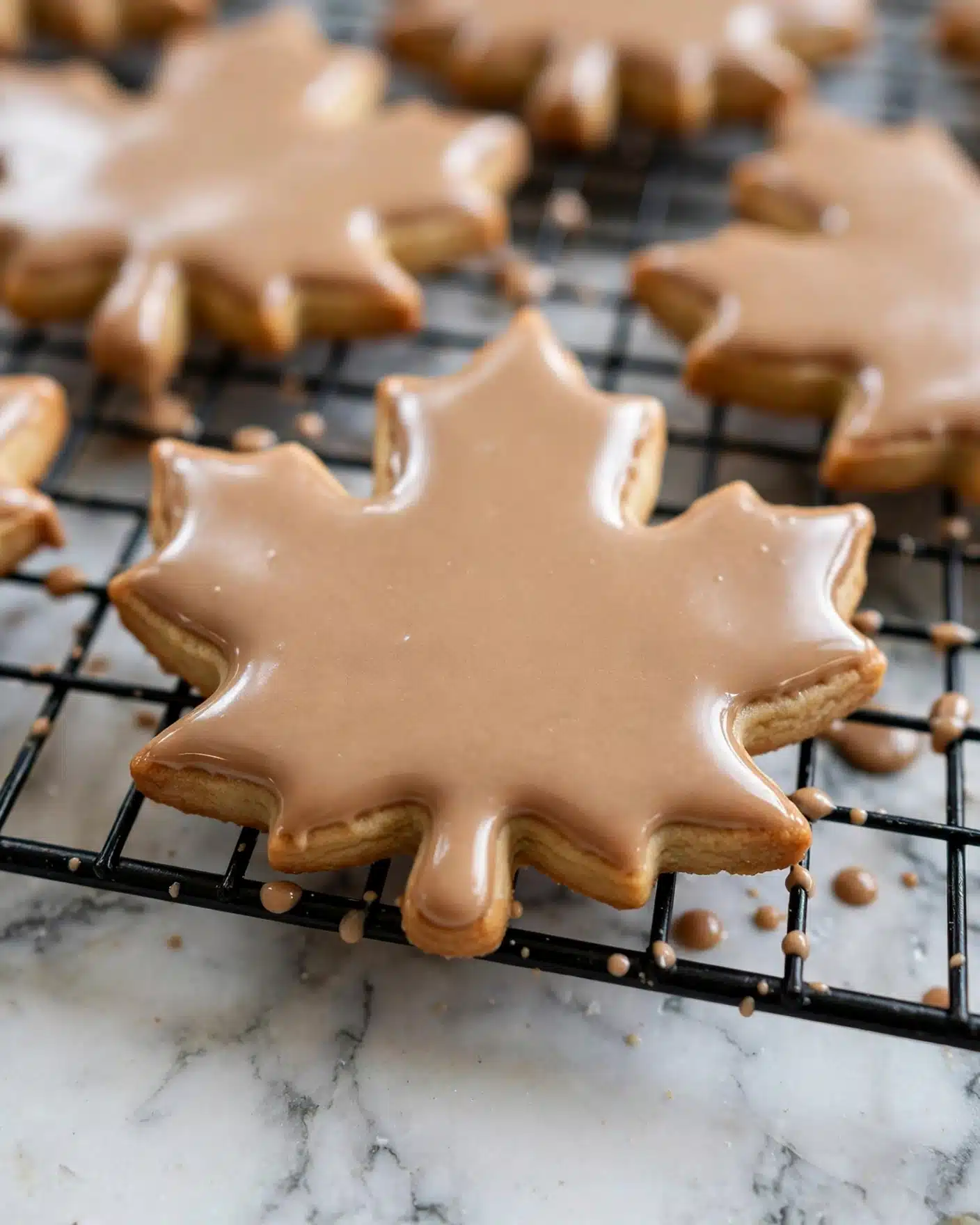Maple Shortbread Cookies with Maple Glaze Recipe 5 The image shows several maple leaf-shaped cookies that are pale yellow in color, each placed inside folded parchment paper envelopes with green and white stripes or pink and white checkered patterns. The envelopes are sealed with decorative tapes in different patterns, like black dots or red designs. The cookies have smooth and slightly shiny surfaces, and the scene is laid out on a white marbled texture. photo taken with an iphone --ar 4:5 --v 7